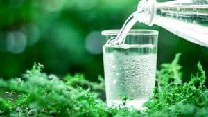 a glass of cool fresh water on natural green background