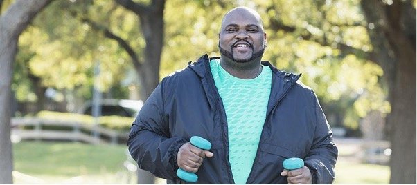 A man holding dumbbells while doing exercise after a weight loss surgery.