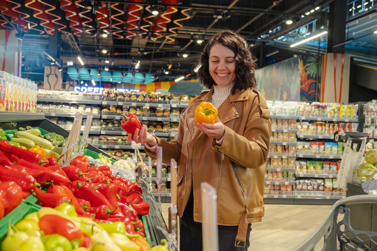 A woman chooses sweet peppers in a supermarket.